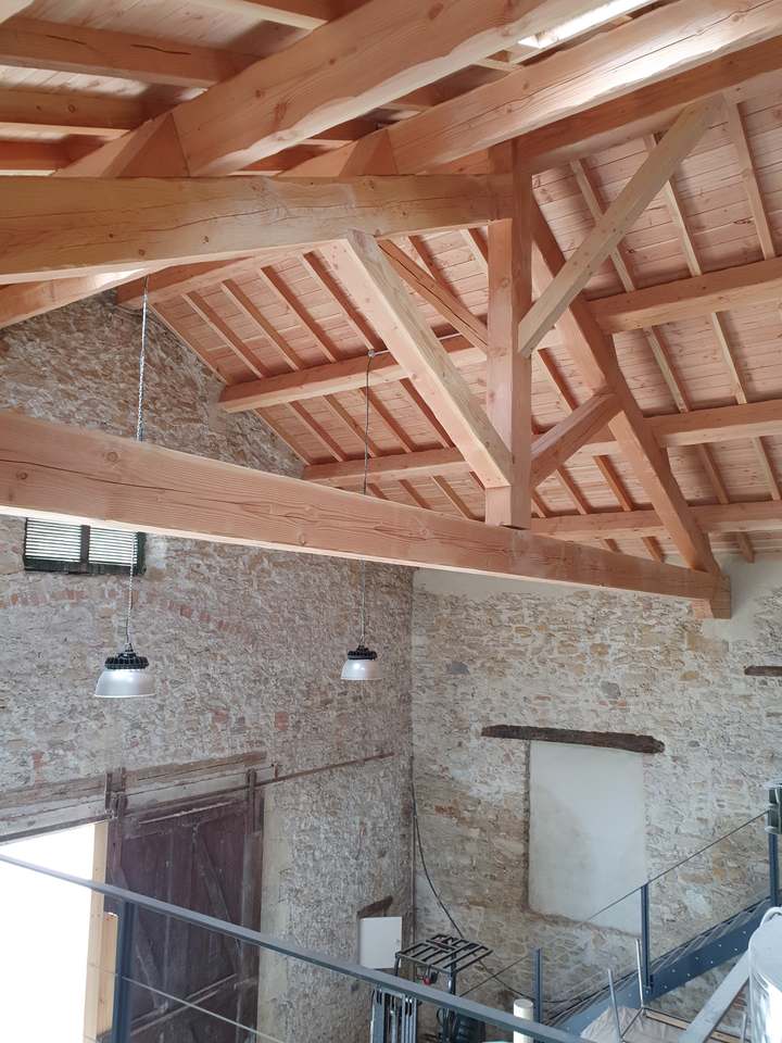 Charpente traditionnelle apparente au-dessus d'un ancien bâtiment en pierre