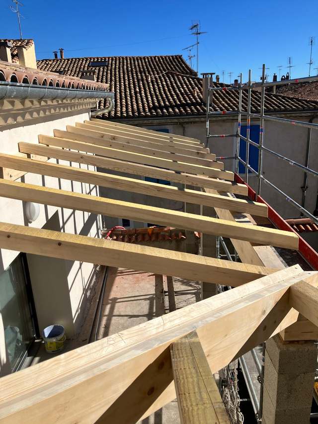 Chevrons et fermette en bois en cours de pose sur un bâtiment