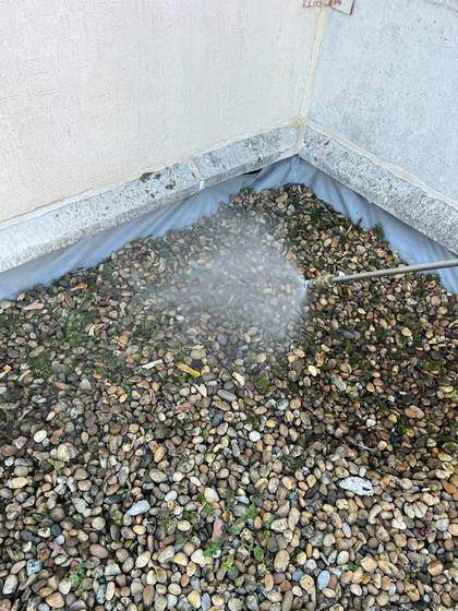 Intervenant nettoyant les gravillons d'une toiture-terrasse au jet