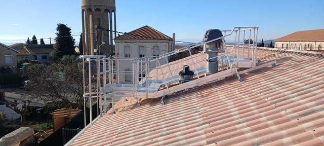 Passerelle en aluminium avec garde-corps et échelle à crinoline sur une toiture en tuiles