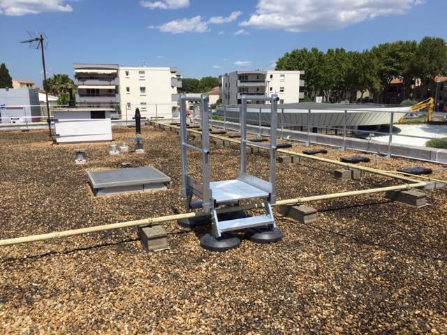 Saut de loup à garde-corps enjambant une canalisation sur une toiture-terrasse